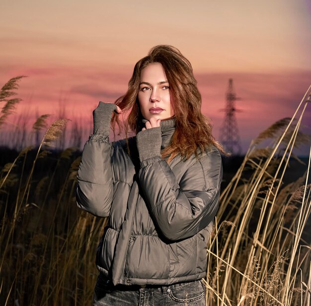 Foto jonge vrouw die tijdens de zonsondergang op het veld tegen de hemel staat