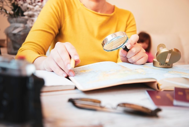 Jonge vrouw die tour plant met reiskaart thuis moeder op zoek naar nieuwe landen om met haar familie te verkennen reistrends en vakantieconcept focus op de hand met vergrootglas