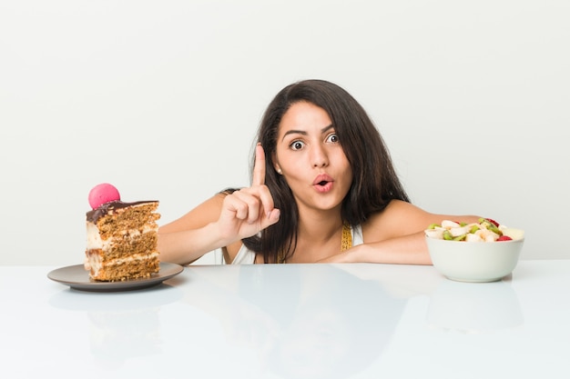 Jonge vrouw die tussen cake of fruit kiest die één of ander groot idee, concept hebben creativiteit.