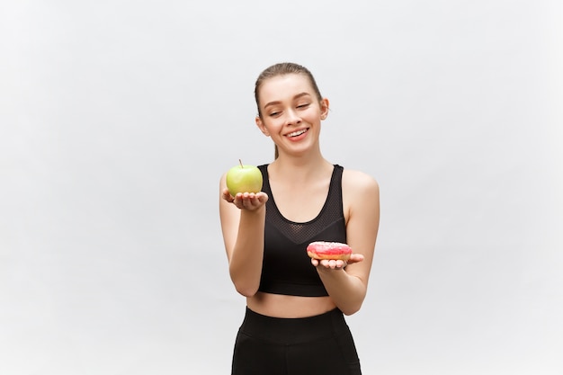 Jonge vrouw die tussen dessert en appel kiest Het concept van het dieetvoedsel.