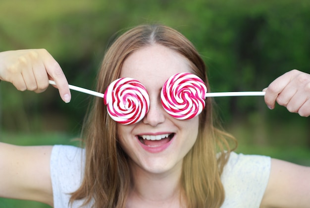 Jonge vrouw die twee lollysuikergoed houdt. Plezier hebben.