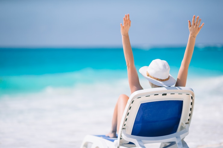 Foto jonge vrouw die van de zon geniet die door perfecte turkooise oceaan zonnebaadt