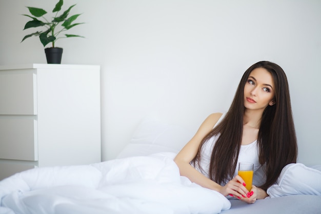 Jonge vrouw die van een glas jus d'orange in de ochtend geniet