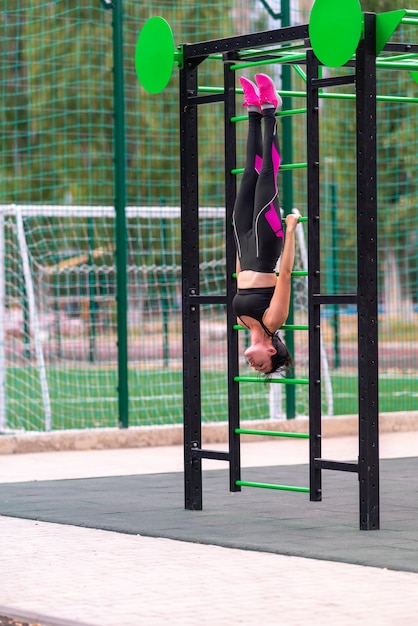 Jonge vrouw die van een gymnastiekladder hangt