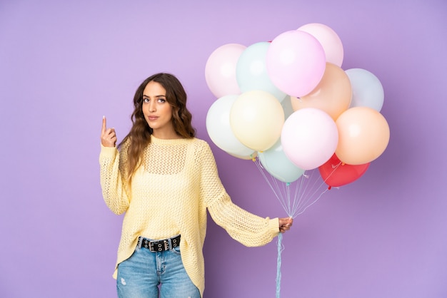 Jonge vrouw die veel ballonnen vangen bij het wijzen met de wijsvinger een geweldig idee