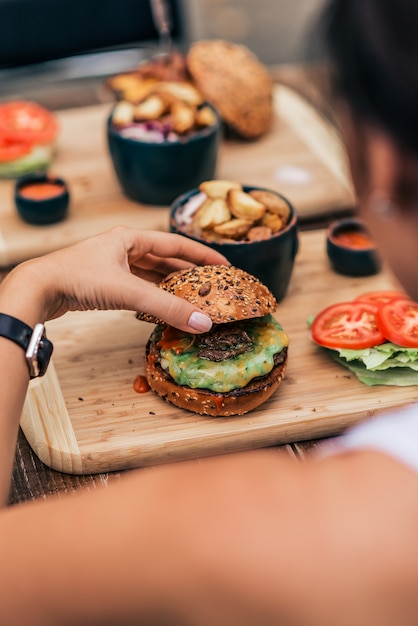 Jonge vrouw die vegetarische hamburger eet. Achteraanzicht.