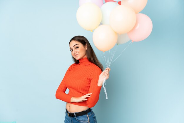 Jonge vrouw die vele ballons bij het blauwe lachen vangt