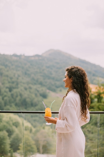 Jonge vrouw die verse jus d'orange drinkt op het buitenterras