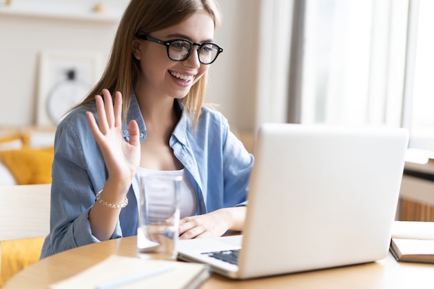 Jonge vrouw die videogesprek via laptop thuis heeft