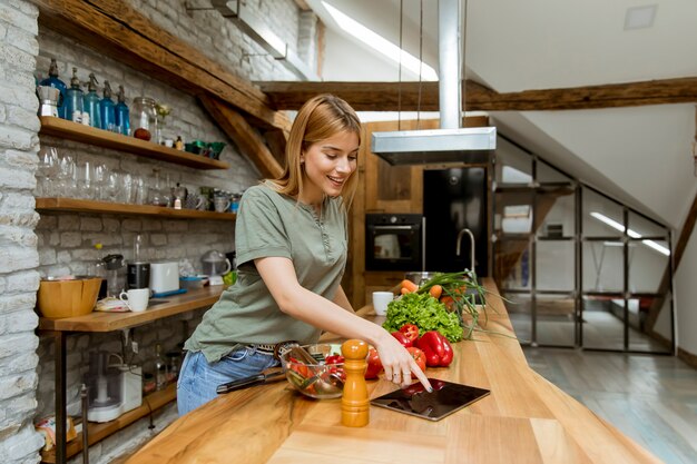 Jonge vrouw die voedsel in de rustieke keuken voorbereidt