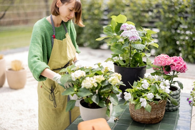 Jonge vrouw die voor bloemen in de tuin zorgt