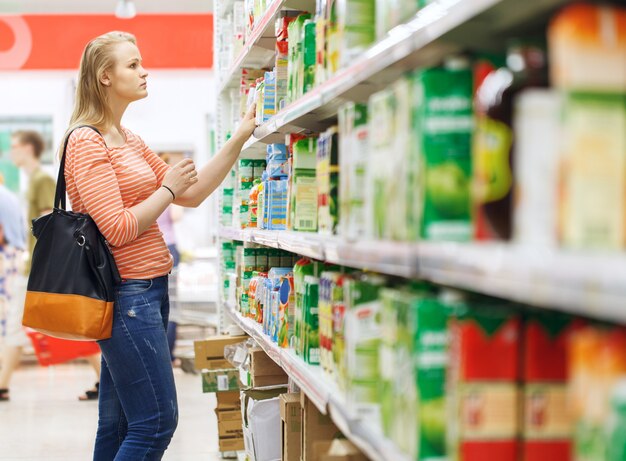 Jonge vrouw die voor sap in supermarkt winkelt