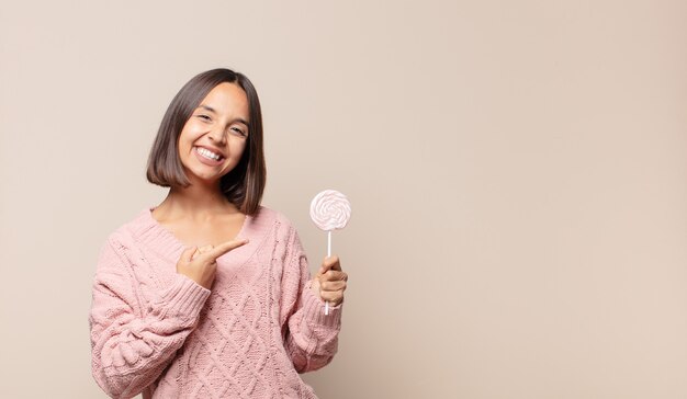 Jonge vrouw die vrolijk glimlacht, zich gelukkig voelt en naar opzij en omhoog wijst, voorwerp in exemplaarruimte toont