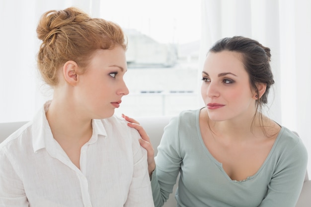 Jonge vrouw die vrouwelijke vriend op bank troost