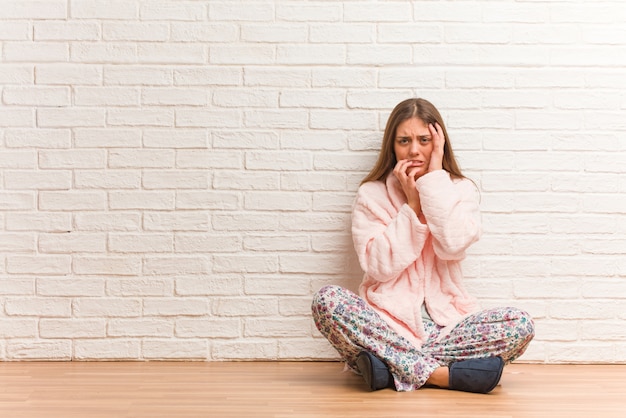 Jonge vrouw die wanhopig en droevig pyjama draagt