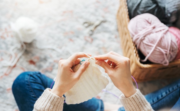 Jonge vrouw die warme sjaal binnenshuis breit