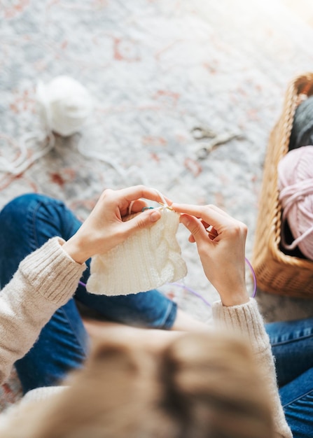 Jonge vrouw die warme sjaal binnenshuis breit