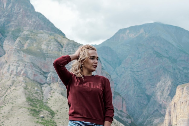 Foto jonge vrouw die wegkijkt terwijl ze tegen de bergketen staat