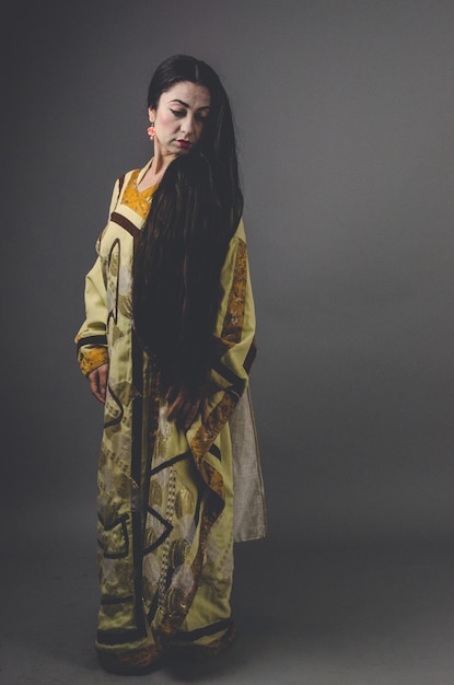 Foto jonge vrouw die wegkijkt terwijl ze tegen een grijze achtergrond staat geisha