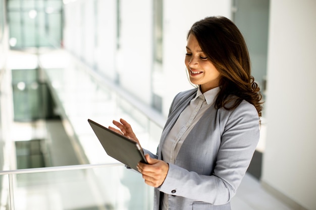 Jonge vrouw die werkt aan digitale tablet in de kantoorgang