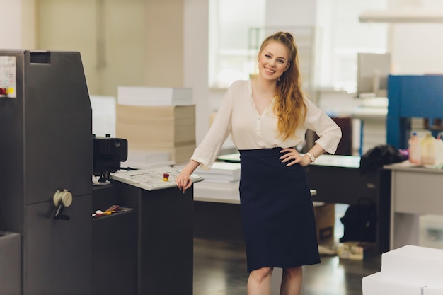 Jonge vrouw die werkt in de drukkerij. Drukpers.