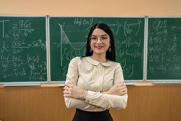 Jonge vrouw die wiskundige vergelijkingen schrijft op het bord in de klas