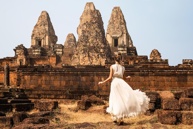 Jonge vrouw die witte gewaadkleding draagt in oude Khmer-ruïnes Angkor Wat