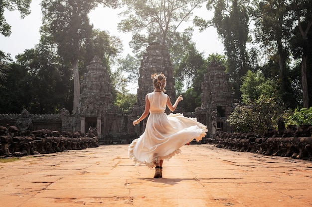 Jonge vrouw die witte gewaadkleding draagt in oude Khmer-ruïnes Angkor Wat