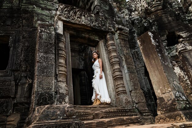 Jonge vrouw die witte gewaadkleding draagt in oude Khmer-ruïnes Angkor Wat