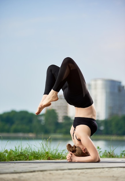 Jonge vrouw die yoga beoefent aan het stadsmeer