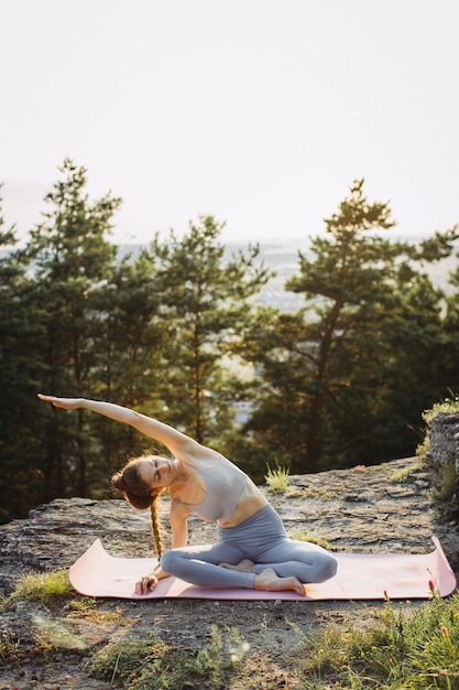 Jonge vrouw die yoga beoefent bij zonsondergang op een prachtige berglocatie