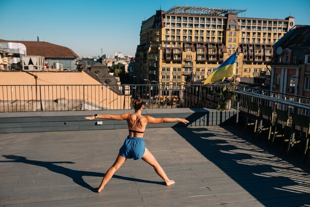 Jonge vrouw die yoga beoefent op het dak van een gebouw