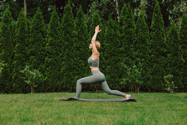 Jonge vrouw die yoga beoefent op het gras in de tuin