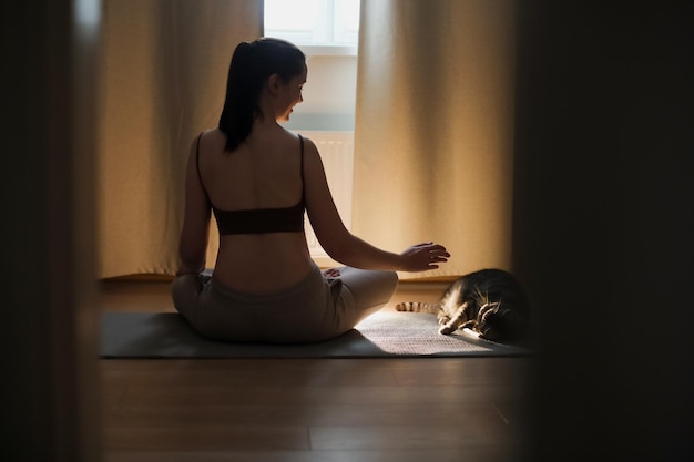 Jonge vrouw die yoga doet en meditatie thuis beoefent, meditatie en concept voor geestelijke gezondheid