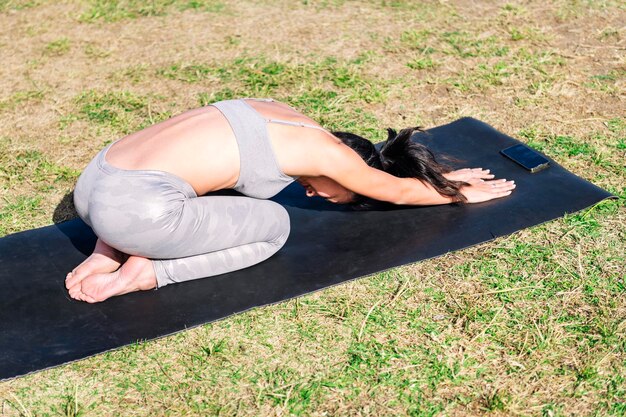 Jonge vrouw die yoga doet en rugstrekkende oefeningen doet