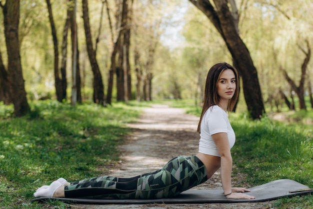 Jonge vrouw die yoga in ochtendpark doet