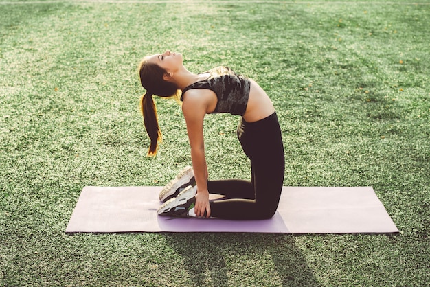 Jonge vrouw die yoga in stadion doet