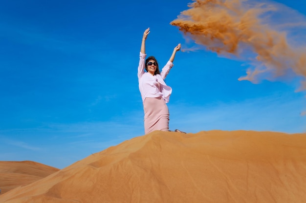 Jonge vrouw die zand gooit in de woestijn van orande