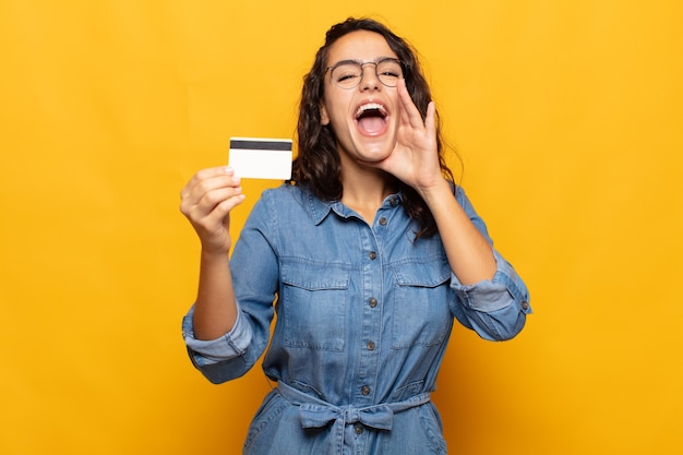 Jonge vrouw die zich blij, opgewonden en positief voelt en een grote schreeuw geeft met de handen naast de mond