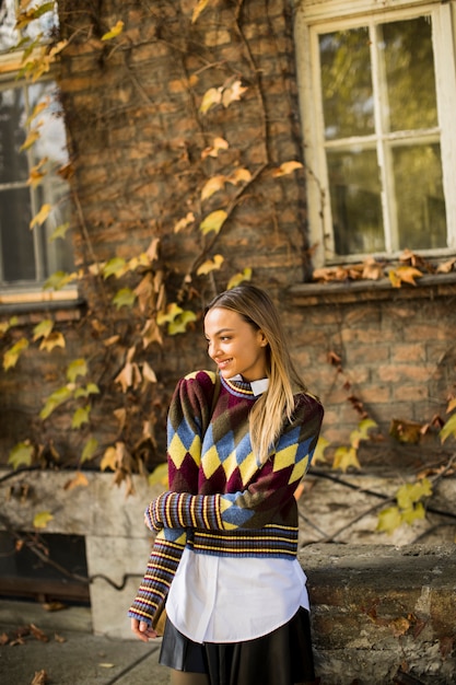 Jonge vrouw die zich buiten bij zonnige de herfstdag bevindt