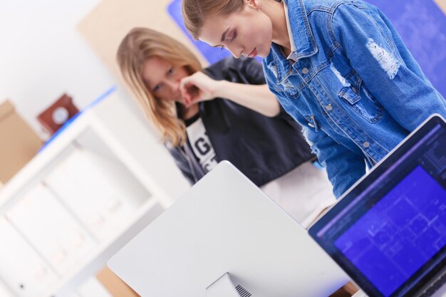 Jonge vrouw die zich dichtbij bureau met instrumentenplan en laptop bevindt