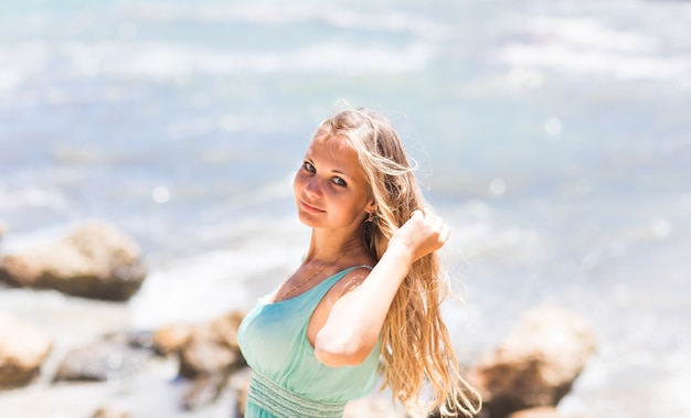 Jonge vrouw die zich dichtbij door het strand zee in blauwe jurk