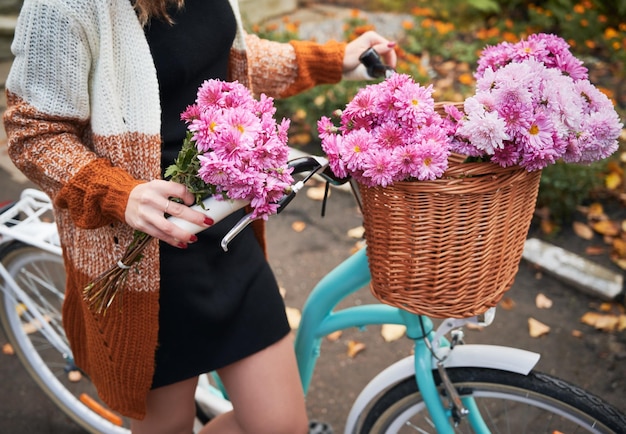 Jonge vrouw die zich dichtbij fiets met roze bloemen bevindt