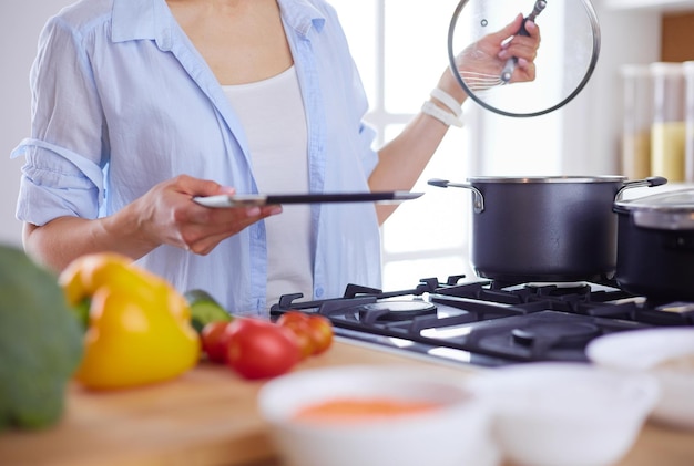 Jonge vrouw die zich door het fornuis in de keuken bevindt