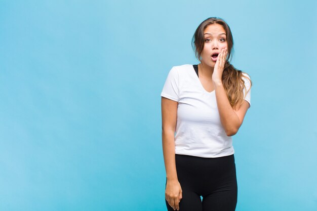 Jonge vrouw die zich geschokt en verbaasd voelt terwijl ze met wijd open mond ongeloof van aangezicht tot hand houdt