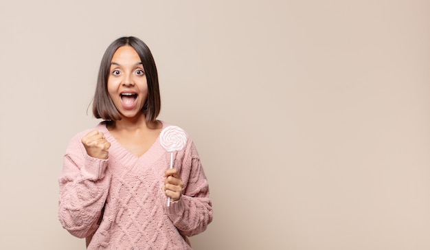 Jonge vrouw die zich geschokt, opgewonden en gelukkig voelt, lacht en succes viert, zeggend wow!