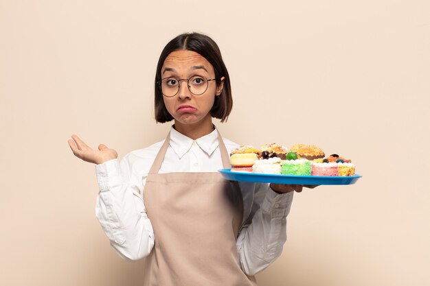 Jonge vrouw die zich in verwarring en verward voelt, twijfelt, weegt of verschillende opties kiest met grappige uitdrukking