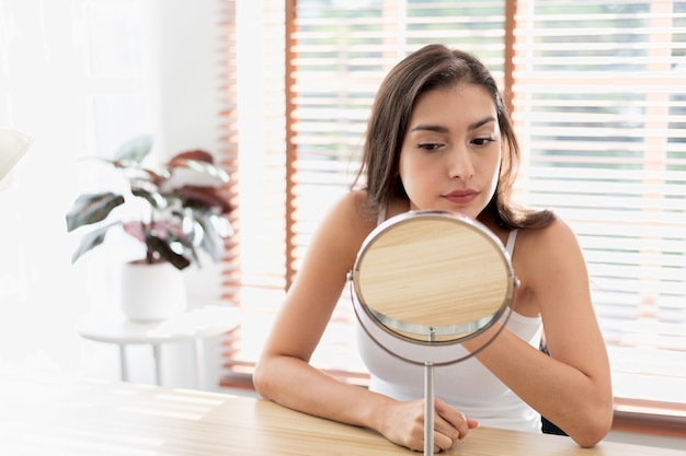 Foto jonge vrouw die zich zorgen maakt over rimpels op haar gezicht meisje dat lotion aanbrengt en geniet van gezonde huidverzorging