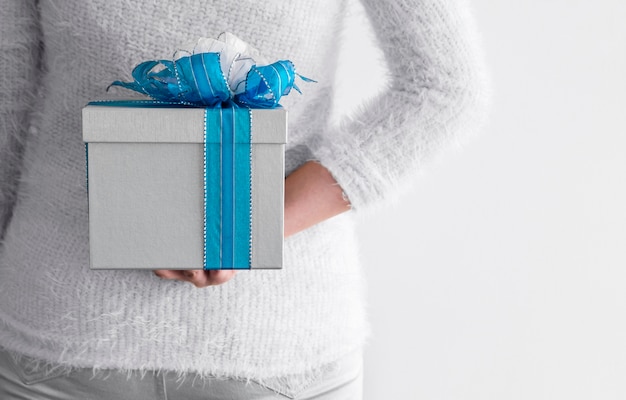 Jonge vrouw die zilveren giftdoos achter haar terug verbergt