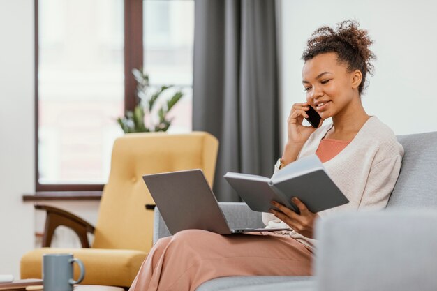 Jonge vrouw die zittend op de bank werkt